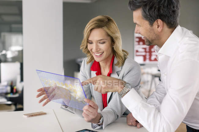 Smiling businessman and businesswoman using futuristic portable device — Stock Photo