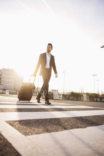 Geschäftsmann läuft mit rollendem Koffer — Stockfoto