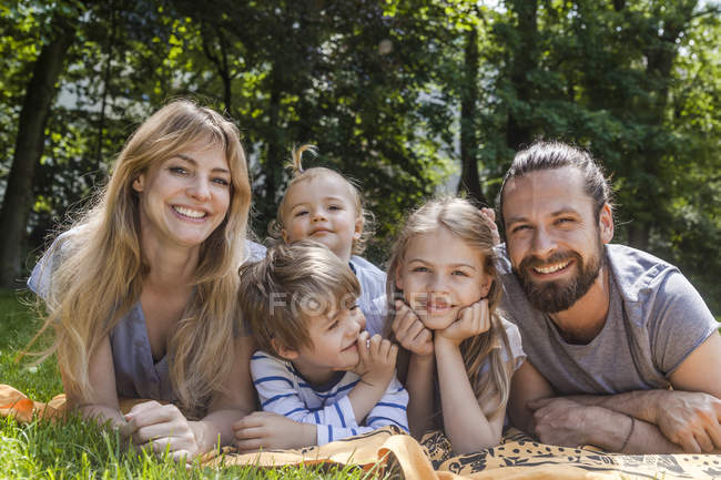 Familia feliz acostada en el prado - foto de stock