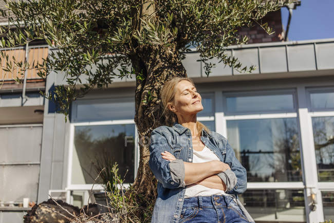 Frau lehnt an Baum — Stockfoto