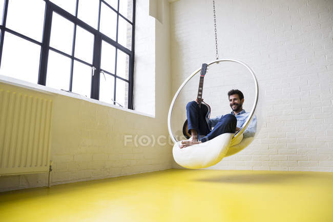 Mann mit Gitarre auf Schaukelstuhl — Stockfoto