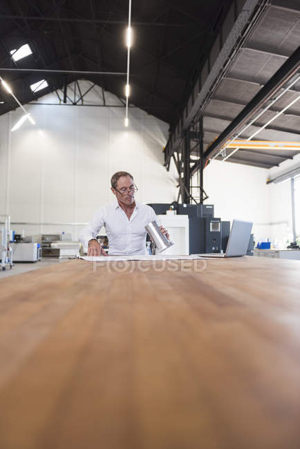 Mann mit Plan und Laptop untersucht Produkt — Stockfoto