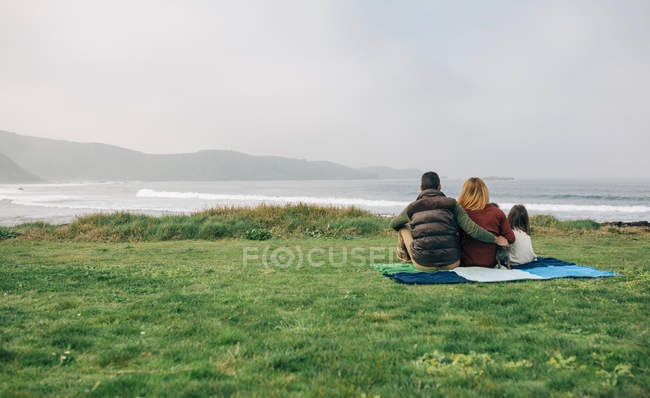 Family with dog sitting on blanket — Stock Photo