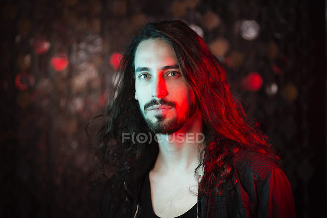 Portrait Of Bearded Long Haired Young Man In Red Light Looking