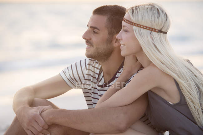 Пара, сидячи на пляжі — стокове фото
