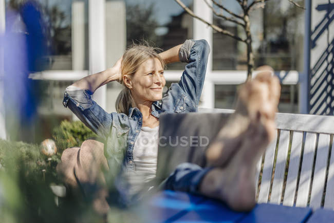 Mulher com laptop relaxante no banco de jardim — Fotografia de Stock