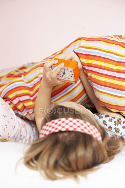 Girl in bed setting the alarm clock — Stock Photo