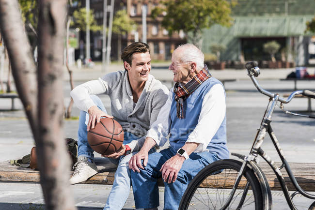 Uomo anziano e nipote con pallacanestro in panchina — Foto stock
