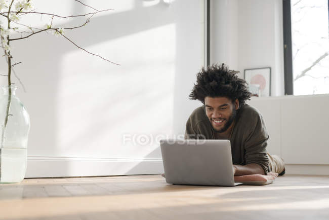 Чоловік лежить на підлозі з ноутбуком — стокове фото