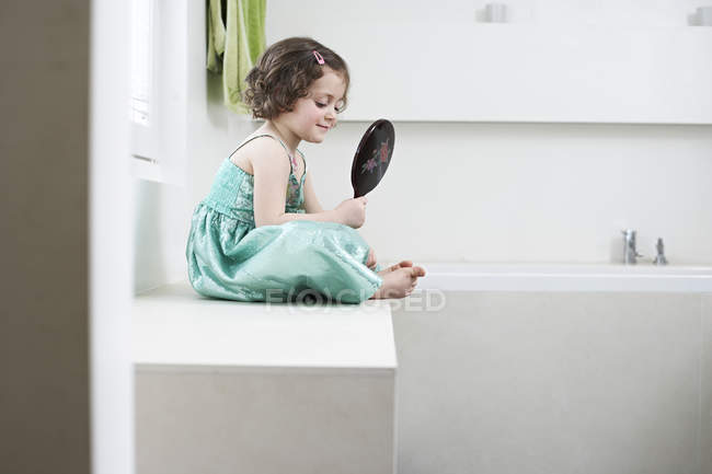 Дівчинка розглядає себе в руках дзеркало — стокове фото