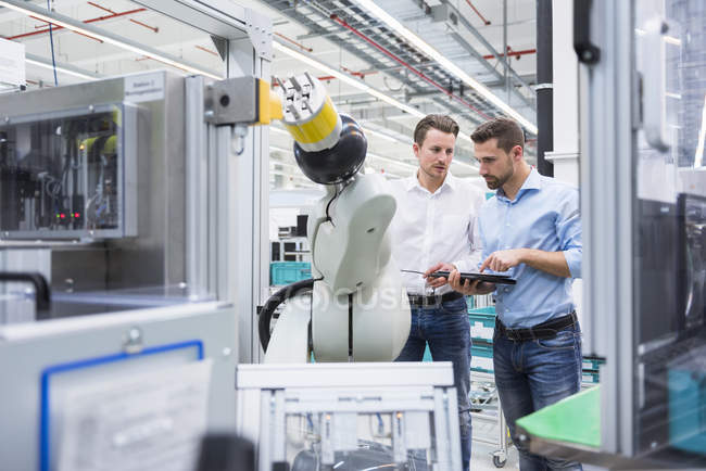 Men with tablet examining assembly robot — Stock Photo