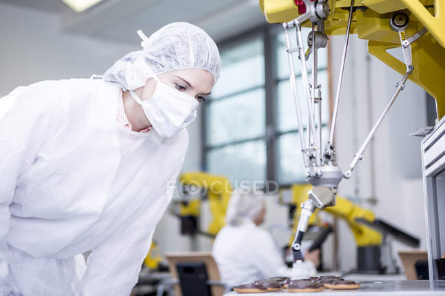 Жінка в заводу, вивчаючи робот обробки файлів cookie — стокове фото