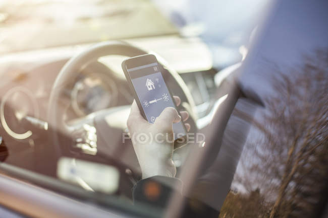 Mann im Auto stellt Geräte zu Hause per Smartphone ein — Stockfoto