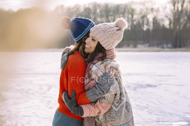 Amigos abraçando no lago congelado — Fotografia de Stock