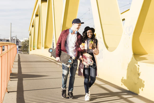 Casal com skates andando na ponte — Fotografia de Stock