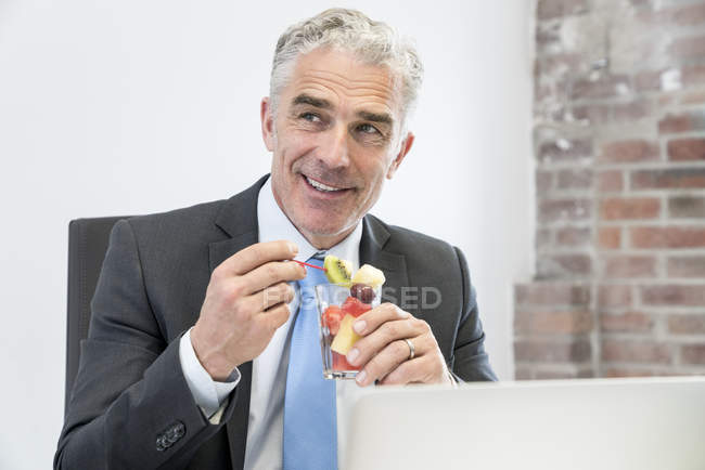 Uomo d'affari mangiare macedonia di frutta — Foto stock