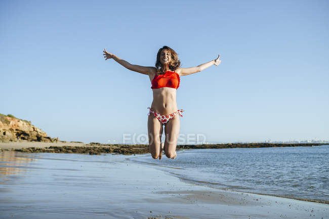 Donna che salta in aria sulla spiaggia — Foto stock