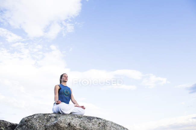 Donna seduta in loto posa su roccia — Foto stock