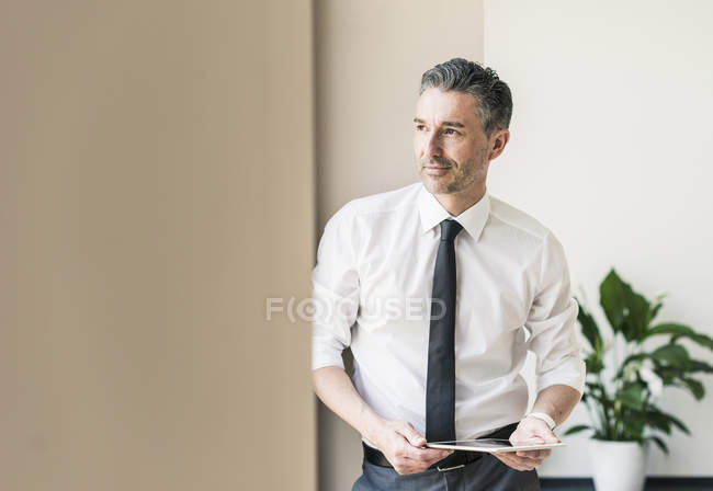 Бізнесмен стоїть в офісі з планшетом — стокове фото