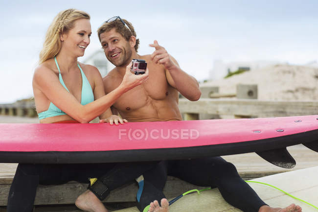Couple with surfboard and camera — Stock Photo