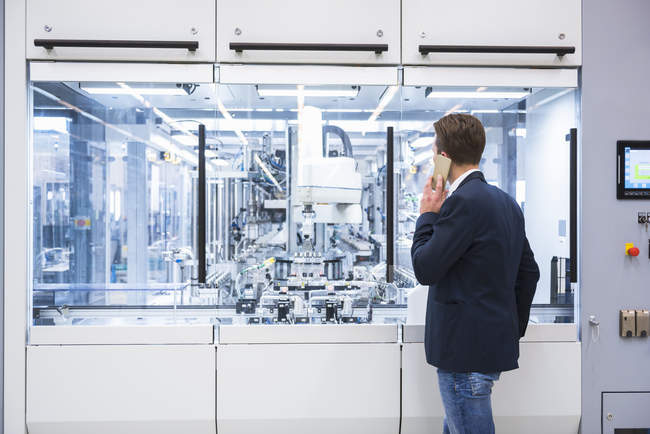 Mann benutzt Handy in Fabrik — Stockfoto