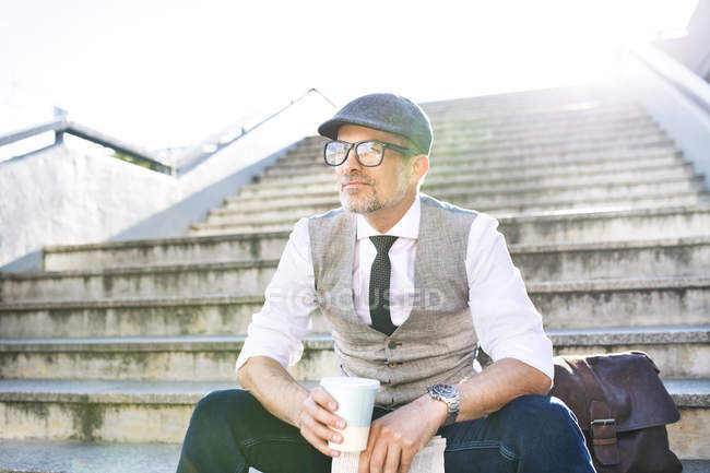 Бізнесмен сидить на сходах з кавою — стокове фото
