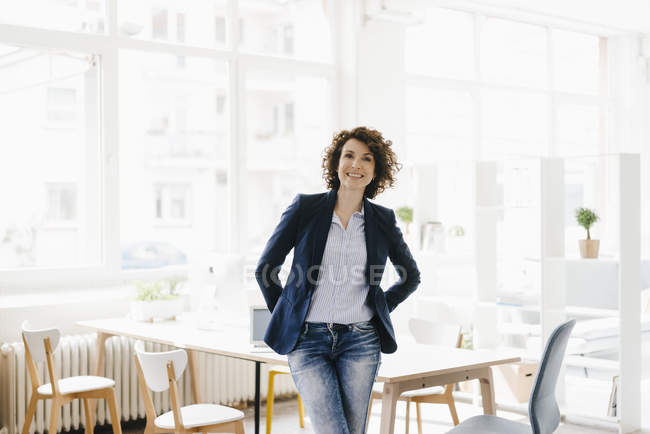 Femme d'affaires assise sur le bureau dans le bureau — Photo de stock