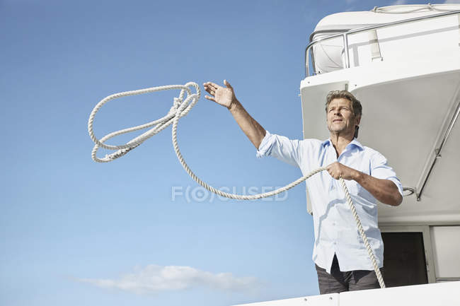 Человек на яхте бросает веревку — стоковое фото