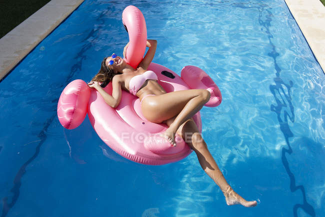 Jovem mulher no flamingo rosa flutuar — Fotografia de Stock