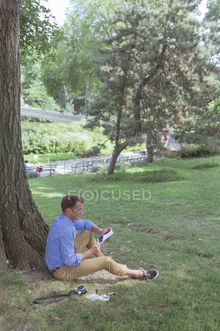 Homem com tablet digital sentado no parque — Fotografia de Stock