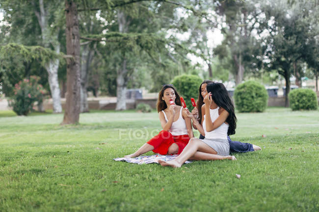 Friends eating popsicles in park — Stock Photo