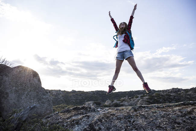 Woman Jumping On Rock Exploration Backlit Stock Photo