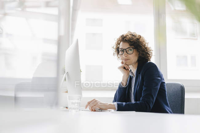 Businesswoman sitting at desk — Stock Photo