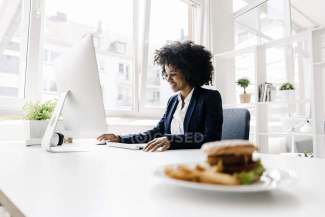 Donna d'affari che lavora con hamburger sulla scrivania — Foto stock