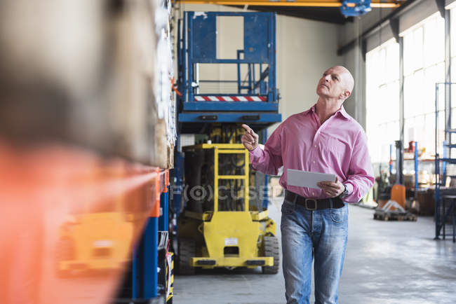 Homem com tablet andando no salão industrial — Fotografia de Stock
