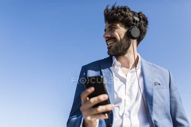 Geschäftsmann mit Smartphone trägt Kopfhörer — Stockfoto