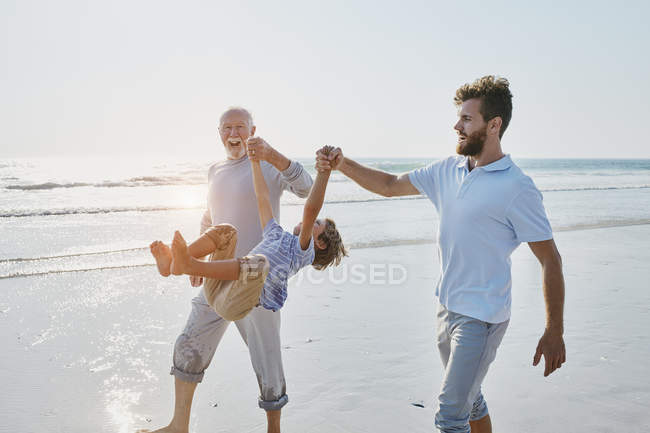 Grandfather with father and son on beach — Stock Photo