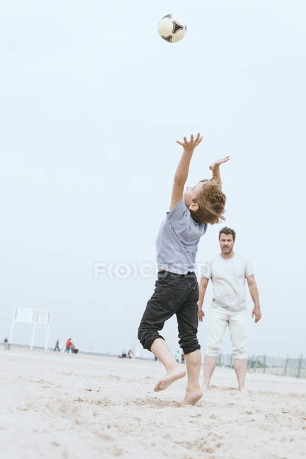Padre e figlioletto che giocano con la palla sulla spiaggia — Foto stock