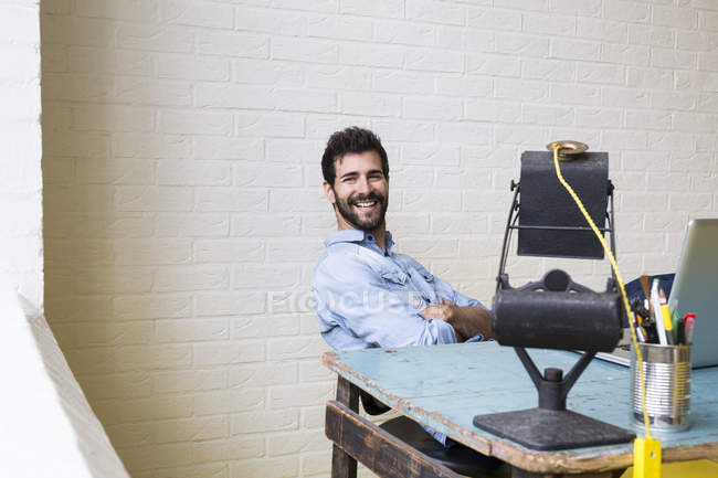 Lächelnder Mann entspannt sich am Schreibtisch — Stockfoto