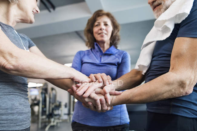 Personas mayores apilándose las manos en el gimnasio - foto de stock
