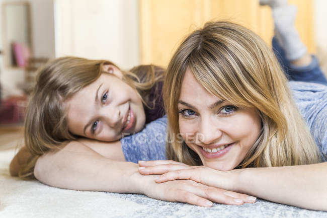 Ritratto di donna bionda sorridente sdraiata sul pavimento con figlia — Foto stock