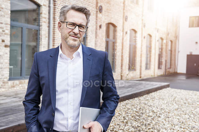 Uomo d'affari con tablet con occhiali e giacca blu — Foto stock
