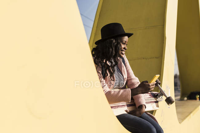 Mulher sentada na ponte usando e smartphone — Fotografia de Stock