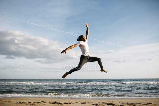 Людина, стрибки в повітря на пляжі — стокове фото