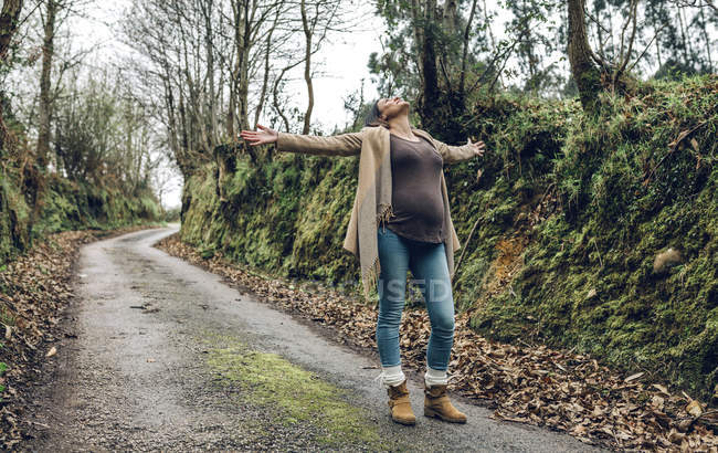 pregnant-woman-raising-arms-in-forest-nature-active-stock-photo