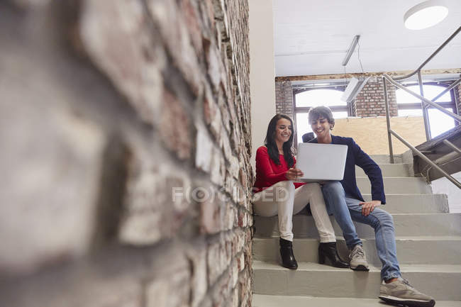 Colleagues sitting on stairs and using laptop — Stock Photo