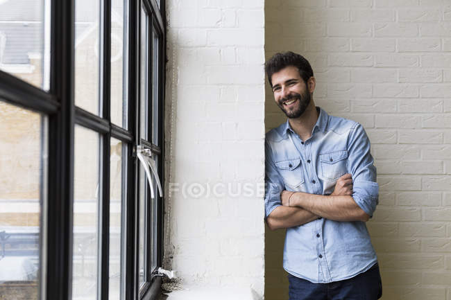 Sonriente hombre apoyado contra una pared - foto de stock