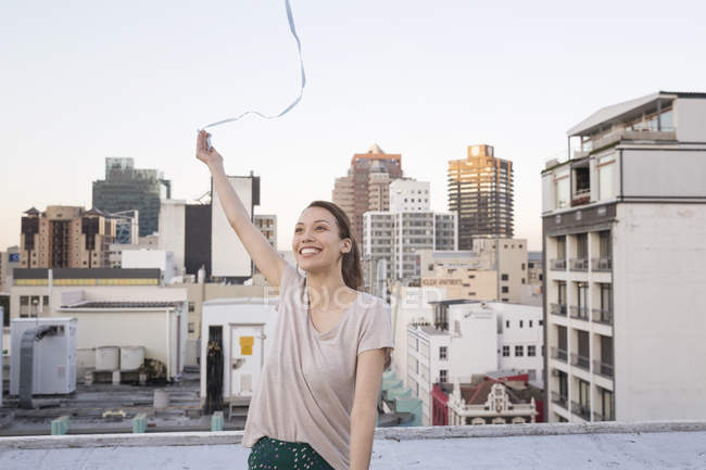 Woman holding ribbon on rooftop terrace — Stock Photo