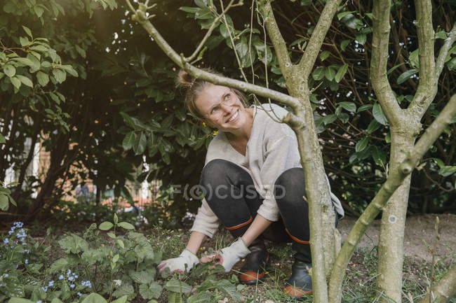 Jeune femme désherbage mauvaises herbes — Photo de stock