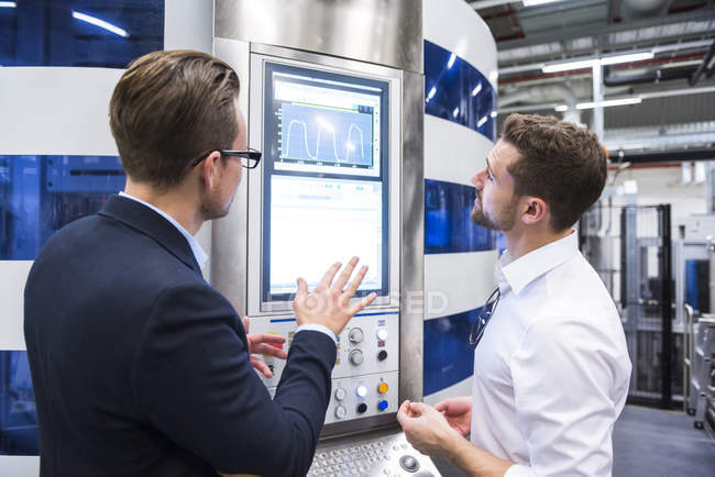 Men looking at screen in factory — Stock Photo